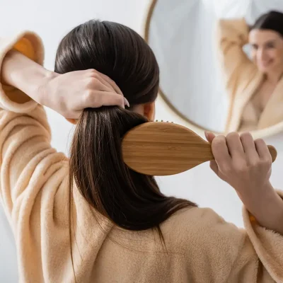 woman brushing full head of hair after PDGF+ hair restoration treatment at NuIQ in Cleveland