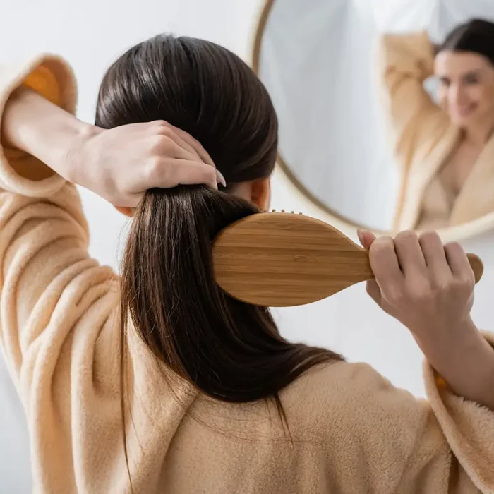 woman brushing full head of hair after PDGF+ hair restoration treatment at NuIQ in Cleveland